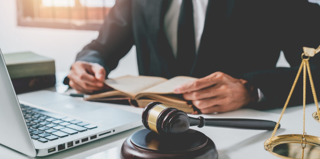 Close up gavel on white desk with Male judge reading legal books background.justice and law concept.